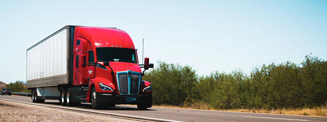 Photo of a red truck on a two-land road.