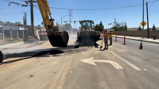 Photo of backhoe and men at work on a Moreno Valley street.