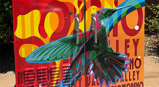 Utility box wrap with two hummingbirds, a colorful background with words and stars. 